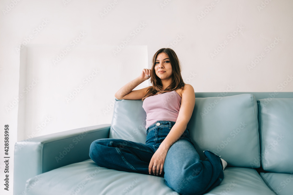 Young calm caucasian woman relaxing, sitting on sofa in modern living room, lazy happy woman resting at home.