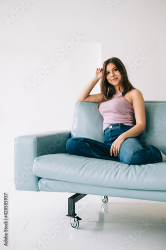 Young calm caucasian woman relaxing, sitting on sofa in modern living room, lazy happy woman resting at home.
