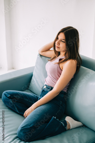 Young calm caucasian woman relaxing, sitting on sofa in modern living room, lazy happy woman resting at home.