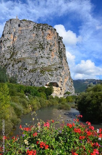Castellane in Alpes-de-Haute-Provence along the route Napoleon, France, church on top of a rock, blue sky with clouds background, stone bridge over Verdon river photo