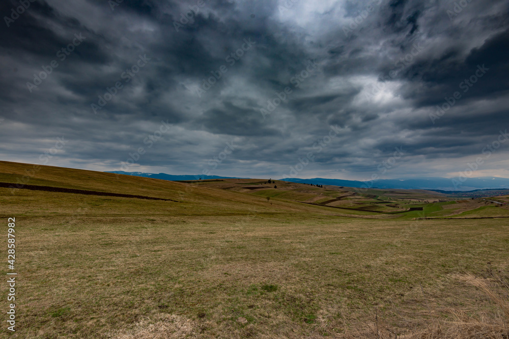 Obraz premium Gathering dramatic stormclouds over the green valley at early spring in Transylvania.
