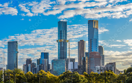 The skyline of Southbank in Melbourne, Australia with light clouds and the light fixtures of the Rod Laver Arena practice courts in the foreground