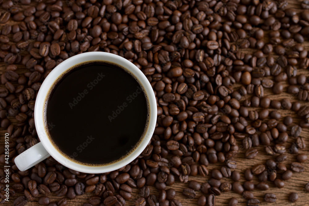 Coffee cup and coffee beans roasted on wooden background,Top view,copy space. Coffee cup and coffee beans roasted on wooden background,Top view,copy space.