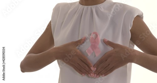 Cropped shot of young woman framing pink purple, which is pinned on white blouse. Symbol of breast cancer awareness. Pink October. Isolated on white background