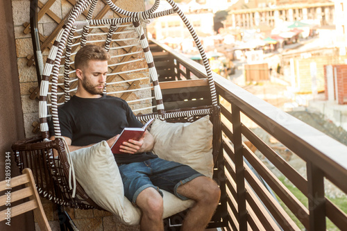 Valokuva Handsome young man in casual clothes studying while sitting on balcony