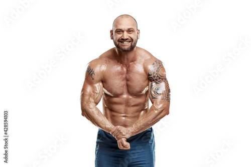 Tattooed male bodybuilder posing over white background. Fitness workout concept, muscle groups, watch your body.