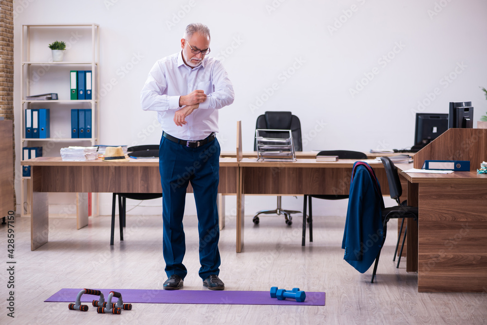 Old businessman employee doing sport exercises in the office Old businessman employee doing sport exercises in the office