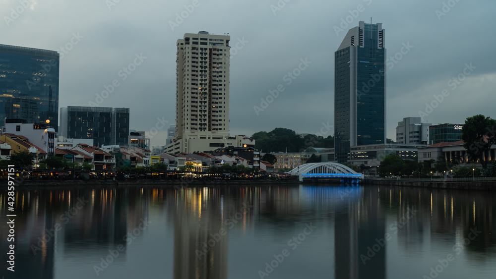 A scene at Boat Quay, Singapore, during sunset with long exposure and reflection of the skyline on the Singapore River