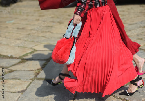 Detail of a fashionable outfit – woman with red dress and red purse
