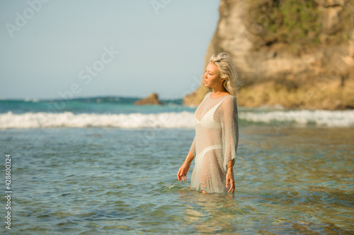 Summer lifestyle portrait of young attractive and sexy blond woman in bikini enjoying relaxed beach holiday at tropical paradise under the sun in Bali Island