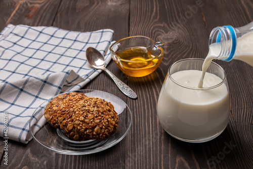 breakfast with oatmeal cookies with cereals and milk poured from a bottle into a glass