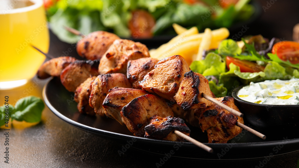 Chicken fillet souvlaki, kebabs on skewers with potato chips, salad and fresh home made tzatziki Chicken fillet souvlaki, kebabs on skewers with potato chips, salad and fresh home made tzatziki