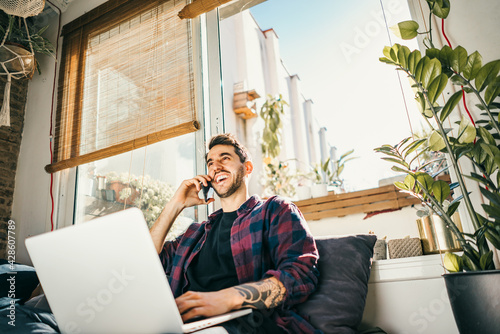 Young man with laptop and smartphone at home. Freelancer. Concept of remote work or study.