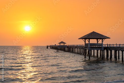 A wooden bridge in the sea with a sunset view