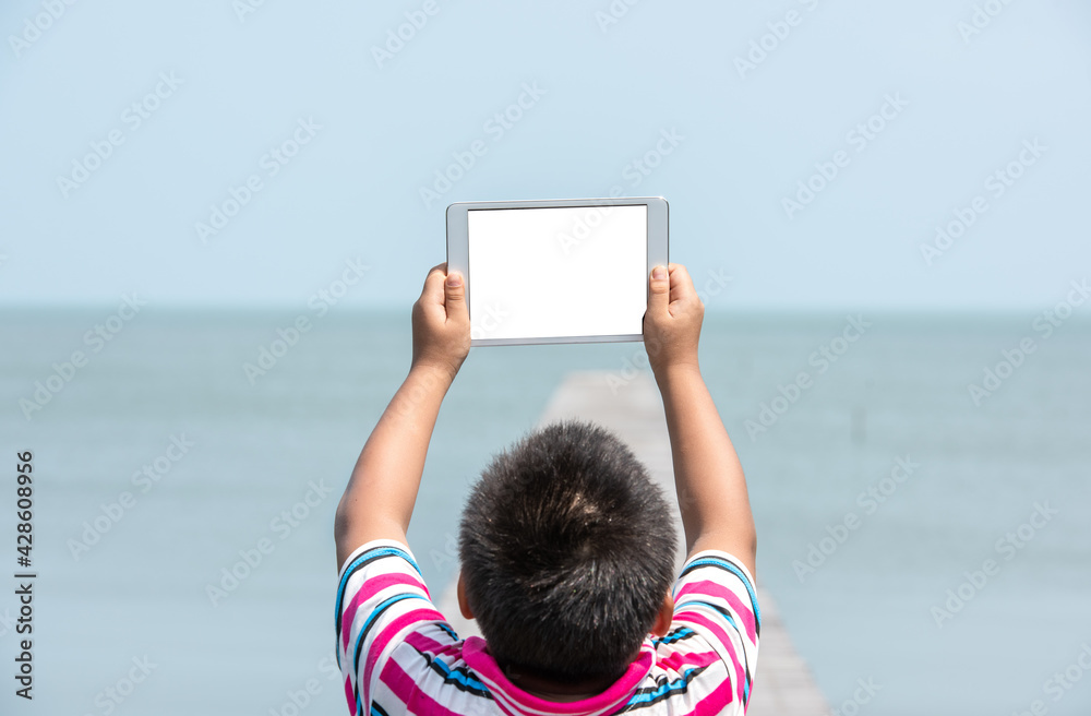 A child with a tablet White screen behind the sea
