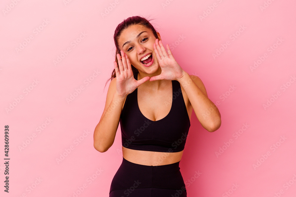 Young sport Indian woman isolated on pink background shouting excited to front.