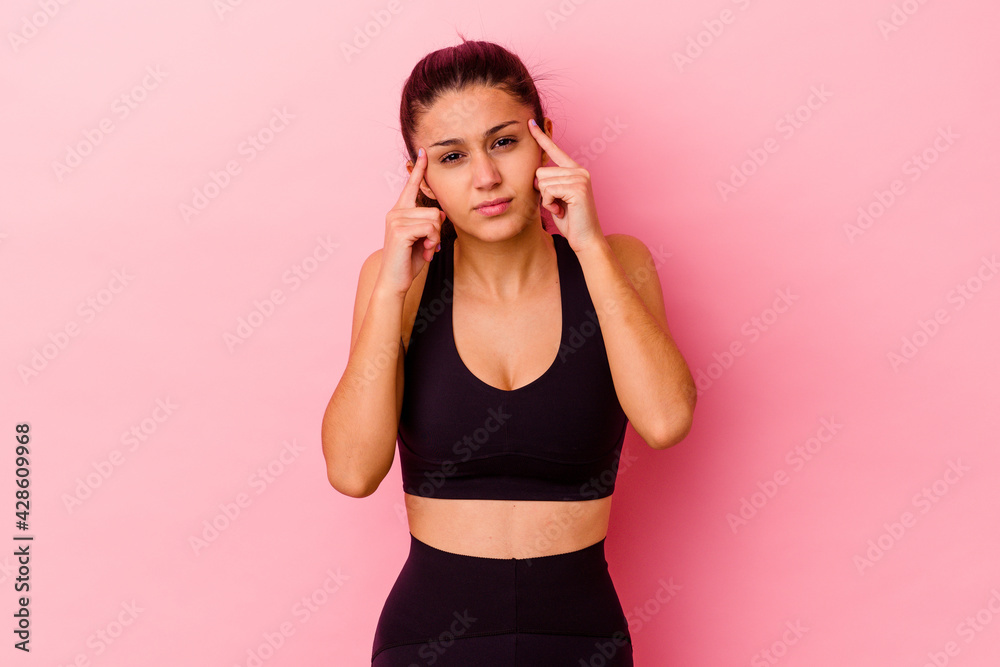 Young sport Indian woman isolated on pink background focused on a task, keeping forefingers pointing head.