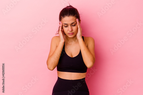 Young sport Indian woman isolated on pink background touching temples and having headache. © Asier