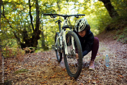 Woman repairs a bicycle in the woods