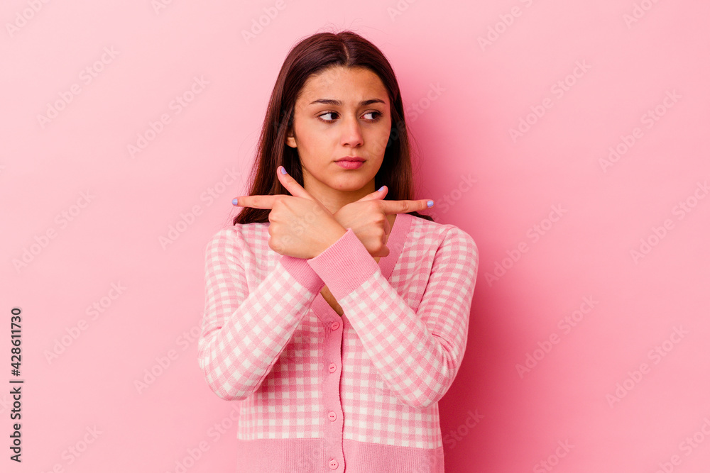 Young Indian woman isolated on pink background points sideways, is trying to choose between two options. Young Indian woman isolated on pink background points sideways, is trying to choose between two options.