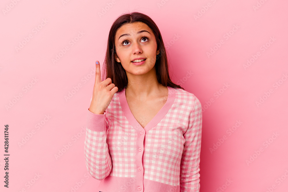 Young Indian woman isolated on pink background indicates with both fore fingers up showing a blank space. Young Indian woman isolated on pink background indicates with both fore fingers up showing a blank space.