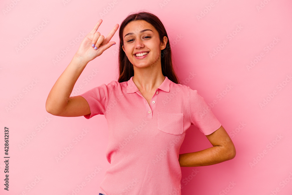 Young Indian woman isolated on pink background showing rock gesture with fingers Young Indian woman isolated on pink background showing rock gesture with fingers