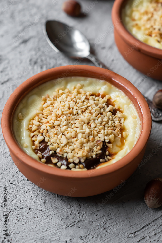 Baked rice pudding turkish milky dessert sutlac in casserole with cinnamon sticks and chopped hazelnuts
