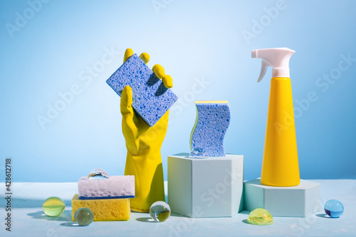 фотографія Creative still life with supplies for cleaning or housekeeping on podiums over blue background