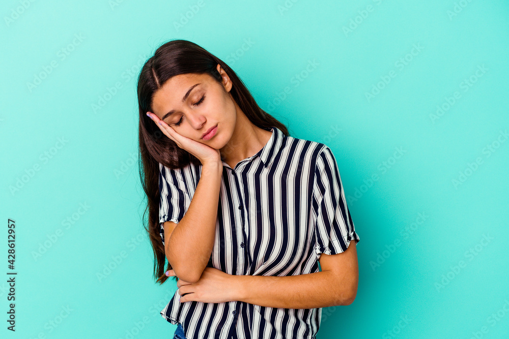 Young Indian woman isolated on blue background who is bored, fatigued and need a relax day. Young Indian woman isolated on blue background who is bored, fatigued and need a relax day.