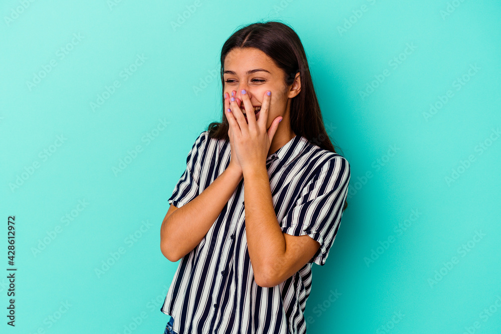 Young Indian woman isolated on blue background laughing about something, covering mouth with hands. Young Indian woman isolated on blue background laughing about something, covering mouth with hands.