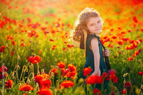 beautiful girl in poppy field enjoys the beauty and aromas.