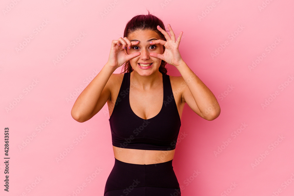 Young sport Indian woman isolated on pink background keeping eyes opened to find a success opportunity.