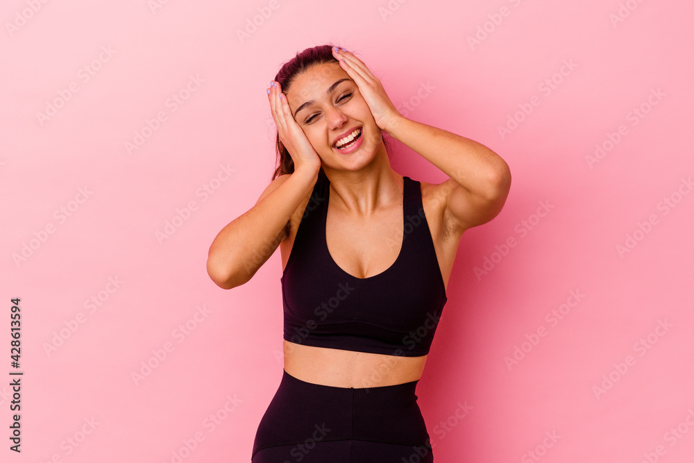 Young sport Indian woman isolated on pink background laughs joyfully keeping hands on head. Happiness concept. Young sport Indian woman isolated on pink background laughs joyfully keeping hands on head. Happiness concept.