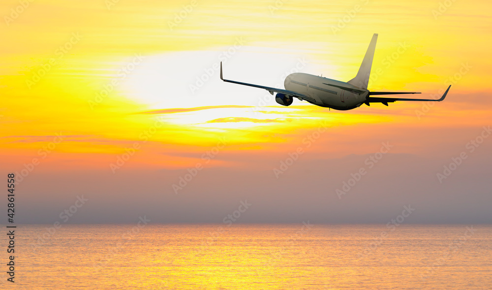 Fototapeta premium Airplane flying over tropical sea at amazing sunset