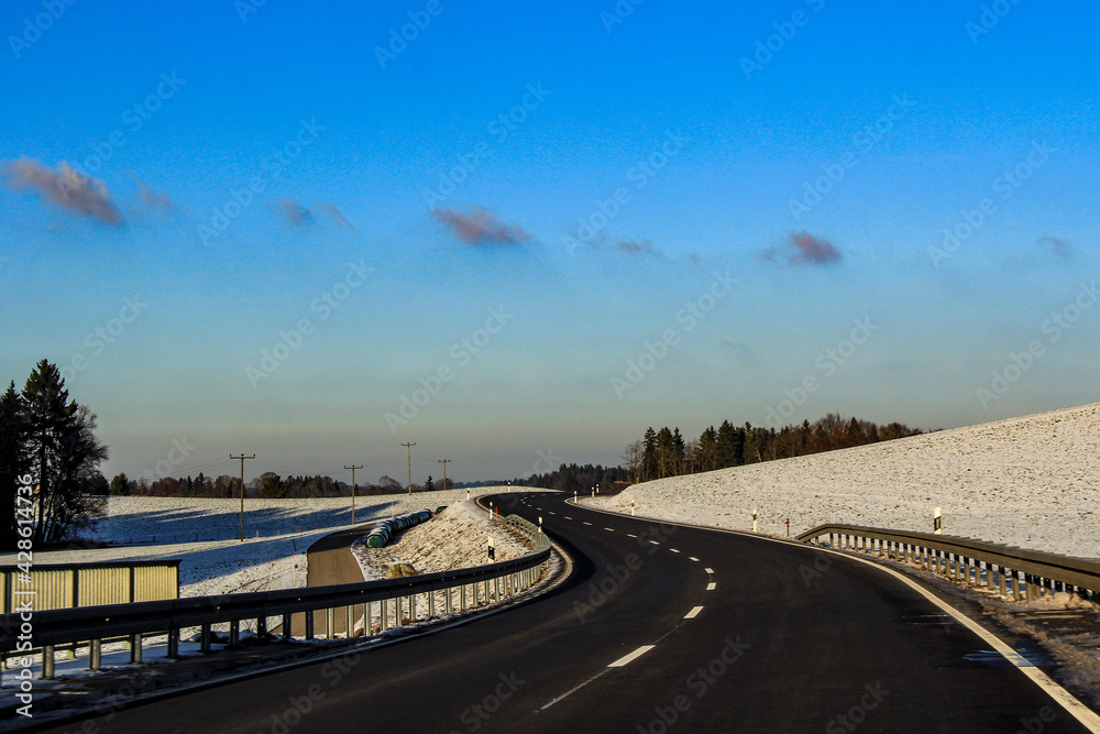 Naklejka premium Curvy road through a snowy field