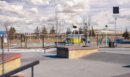 An empty skate park and outdoor splash park with solar panels recharging LED street lights in the urban community of Airdrie Alberta Canada.