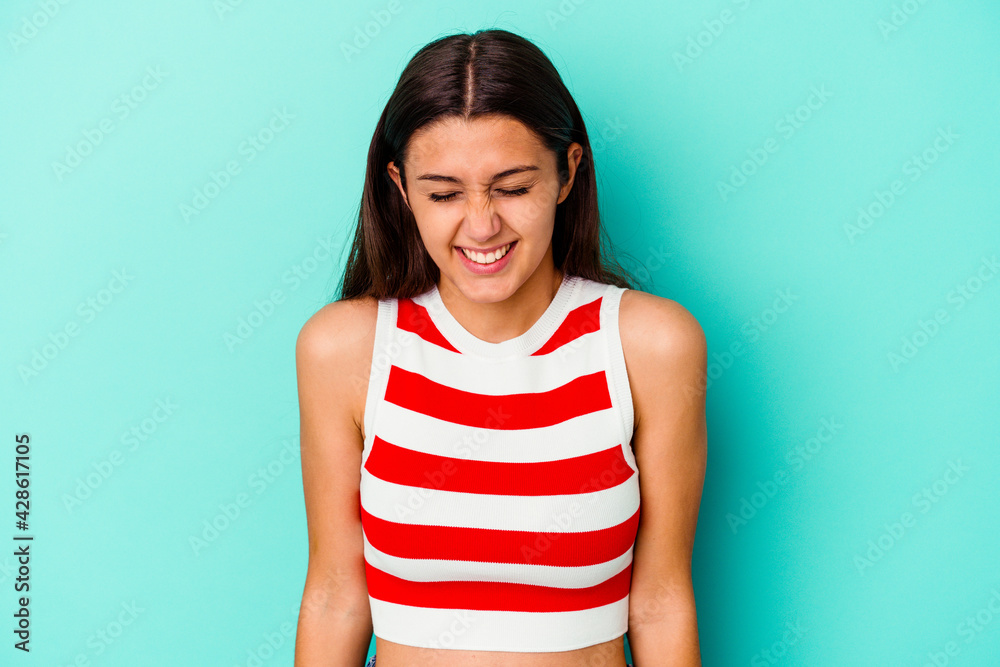 Young Indian woman isolated on blue background laughs and closes eyes, feels relaxed and happy. Young Indian woman isolated on blue background laughs and closes eyes, feels relaxed and happy.
