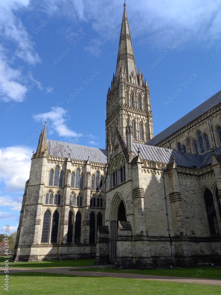 The Anglican cathedral of Salisbury in Wiltshire against a blue sky, including the tower and spire and showcasing the Gothic architecture.