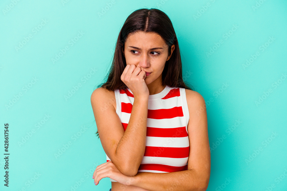 Young Indian woman isolated on blue background biting fingernails, nervous and very anxious. Young Indian woman isolated on blue background biting fingernails, nervous and very anxious.