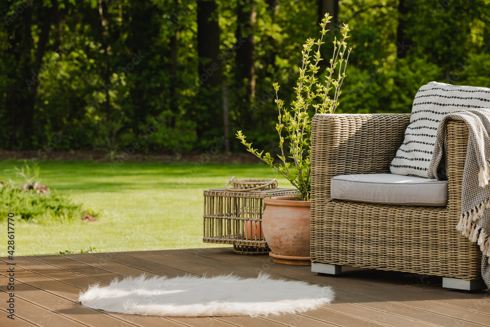 Wicker armchair with pillow on green terrace in beautiful garden - obrazy, fototapety, plakaty 