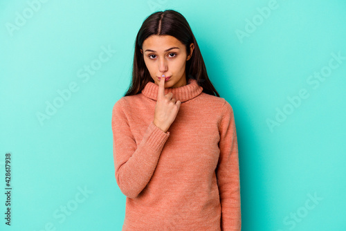 Young Indian woman isolated on blue background thinking and looking up, being reflective, contemplating, having a fantasy.