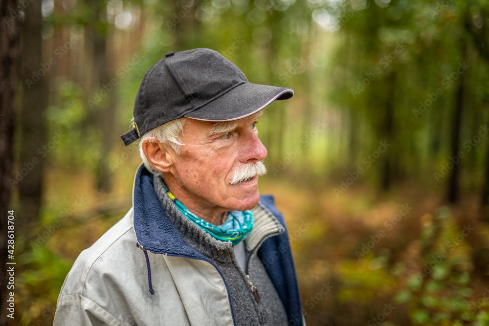 A mature man wearing a cap walking in the woods during the day. A mature man wearing a cap walking in the woods during the day.