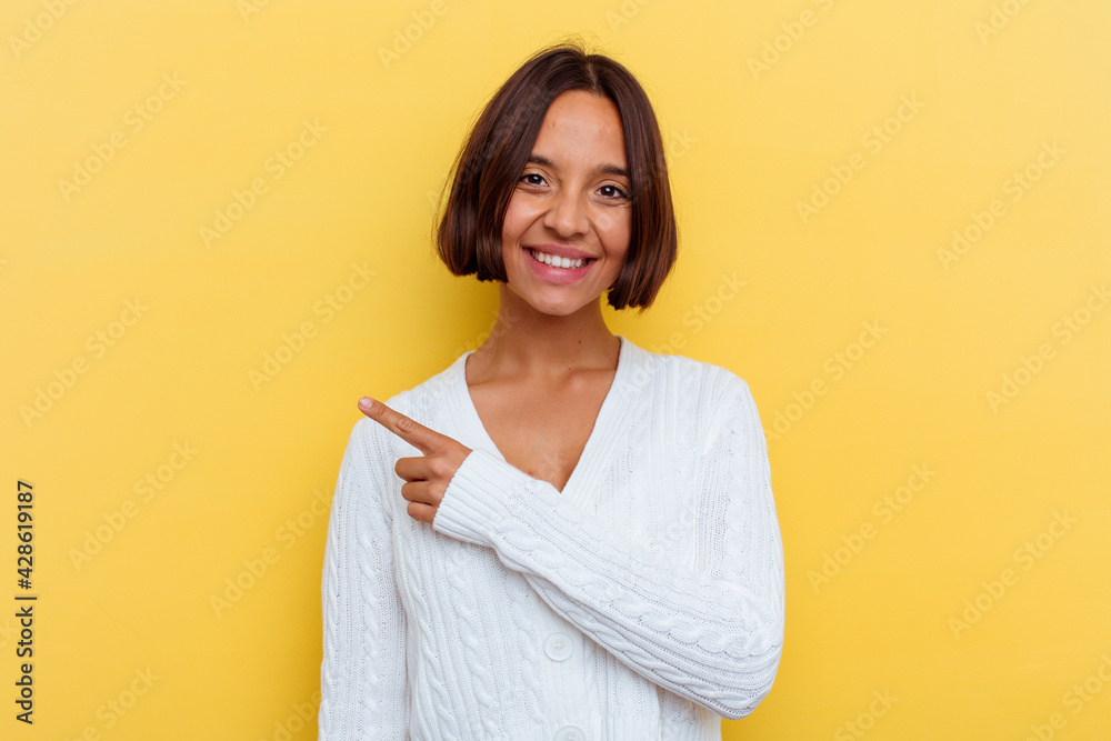 Young mixed race woman isolated on yellow background smiling and pointing aside, showing something at blank space. Young mixed race woman isolated on yellow background smiling and pointing aside, showing something at blank space.