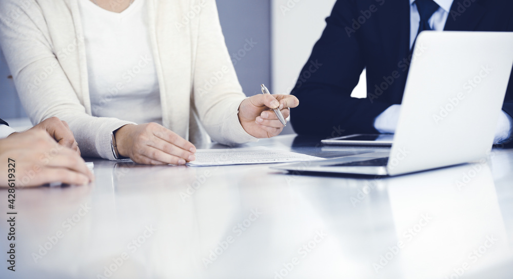 Business people discussing contract working together at meeting in modern office. Unknown businessman and woman with colleagues or lawyers at negotiation