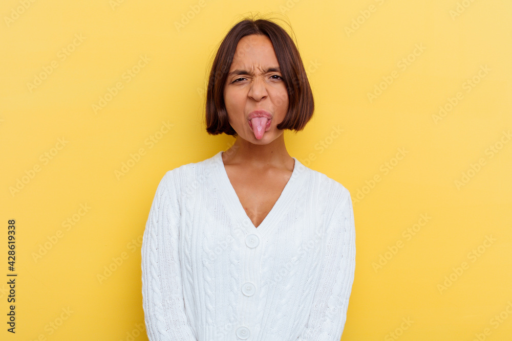Young mixed race woman isolated on yellow background funny and friendly sticking out tongue. Young mixed race woman isolated on yellow background funny and friendly sticking out tongue.