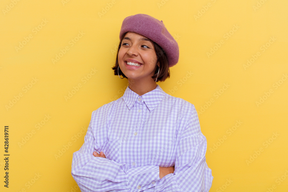 Young mixed race woman wearing a beret isolated on yellow background smiling confident with crossed arms. Young mixed race woman wearing a beret isolated on yellow background smiling confident with crossed arms.