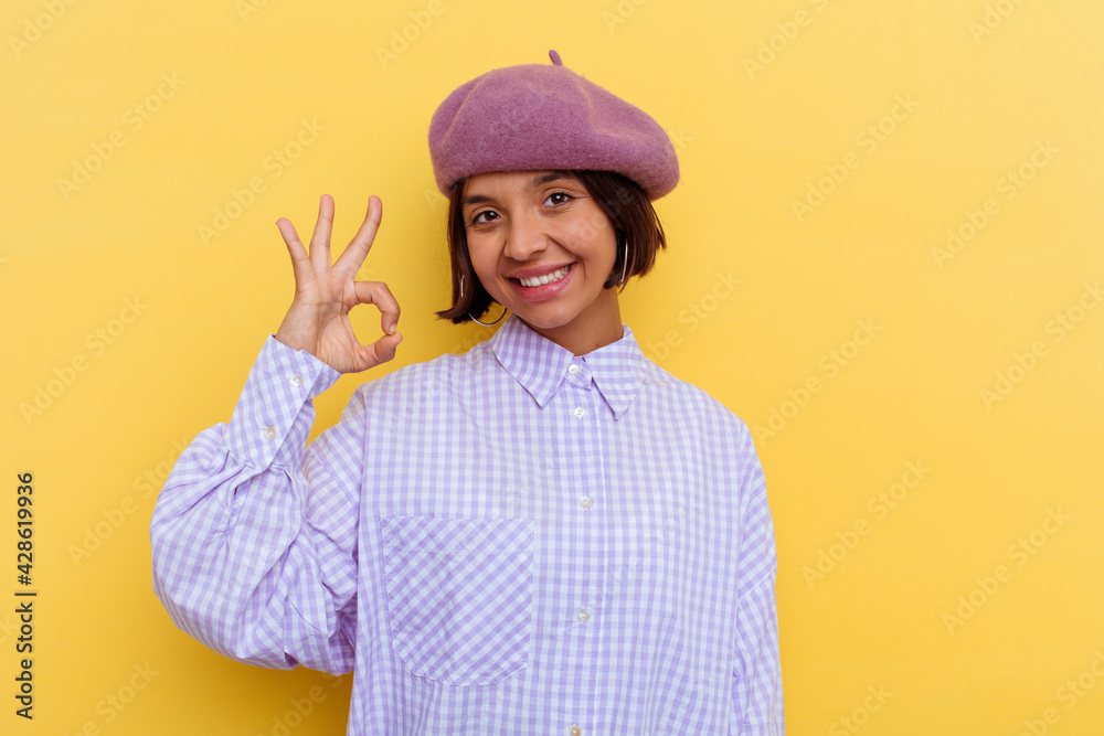 Young mixed race woman wearing a beret isolated on yellow background cheerful and confident showing ok gesture. Young mixed race woman wearing a beret isolated on yellow background cheerful and confident showing ok gesture.