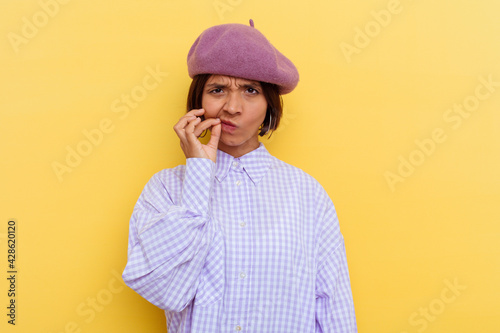 Young mixed race woman wearing a beret isolated on yellow background with fingers on lips keeping a secret.