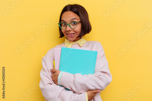 Young mixed race student woman isolated on yellow background