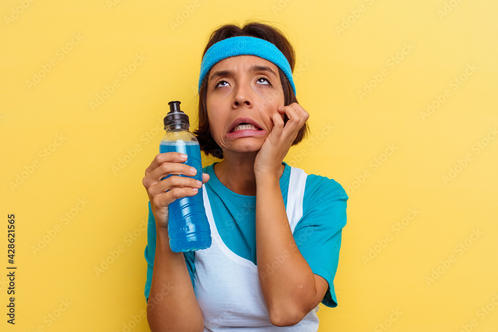 Young sport mixed race woman isolated drinking an energy drink on yellow background Young sport mixed race woman isolated drinking an energy drink on yellow background